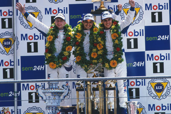 Allan McNish, Stéphane Ortelli, Laurent Aiello, Le Mans 1998de Mobil 1 logosunun önünde podyumda